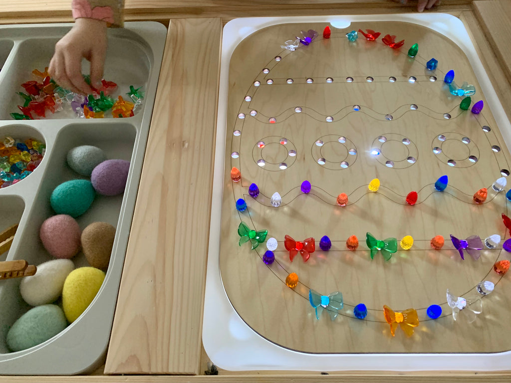 Light Up Easter Egg Flisat insert with colorful light pegs and felt eggs beside storage tray on wooden table