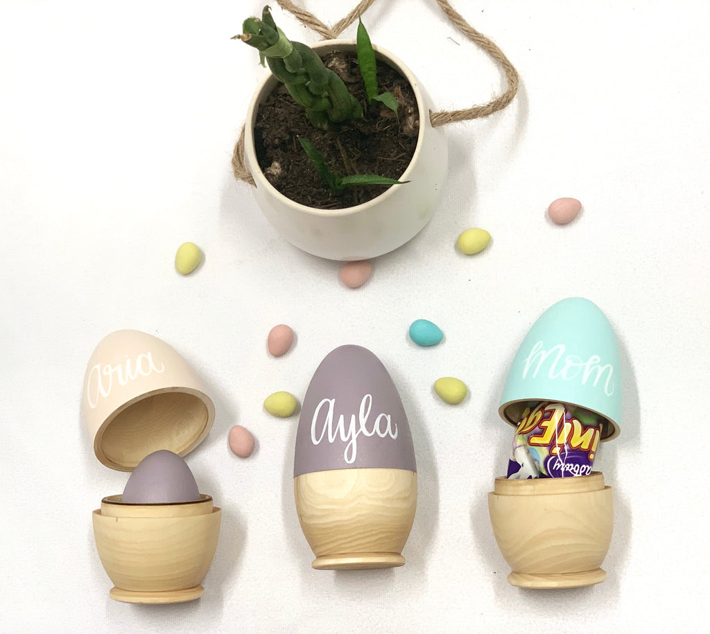 Set of three personalized hollow wooden Easter eggs in natural and pastel colors with candy and small decorations inside