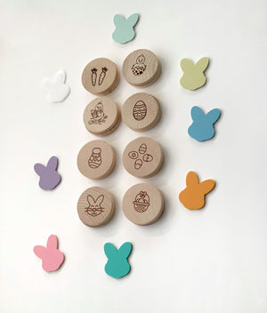Round wooden Easter memory game pieces with engraved holiday images surrounded by colorful bunny shapes on white background