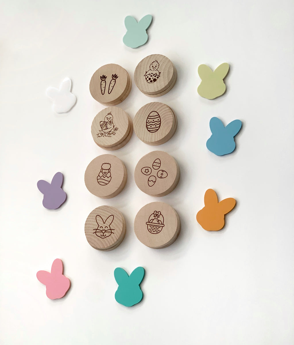 Round wooden Easter memory game pieces with engraved holiday images surrounded by colorful bunny shapes on white background