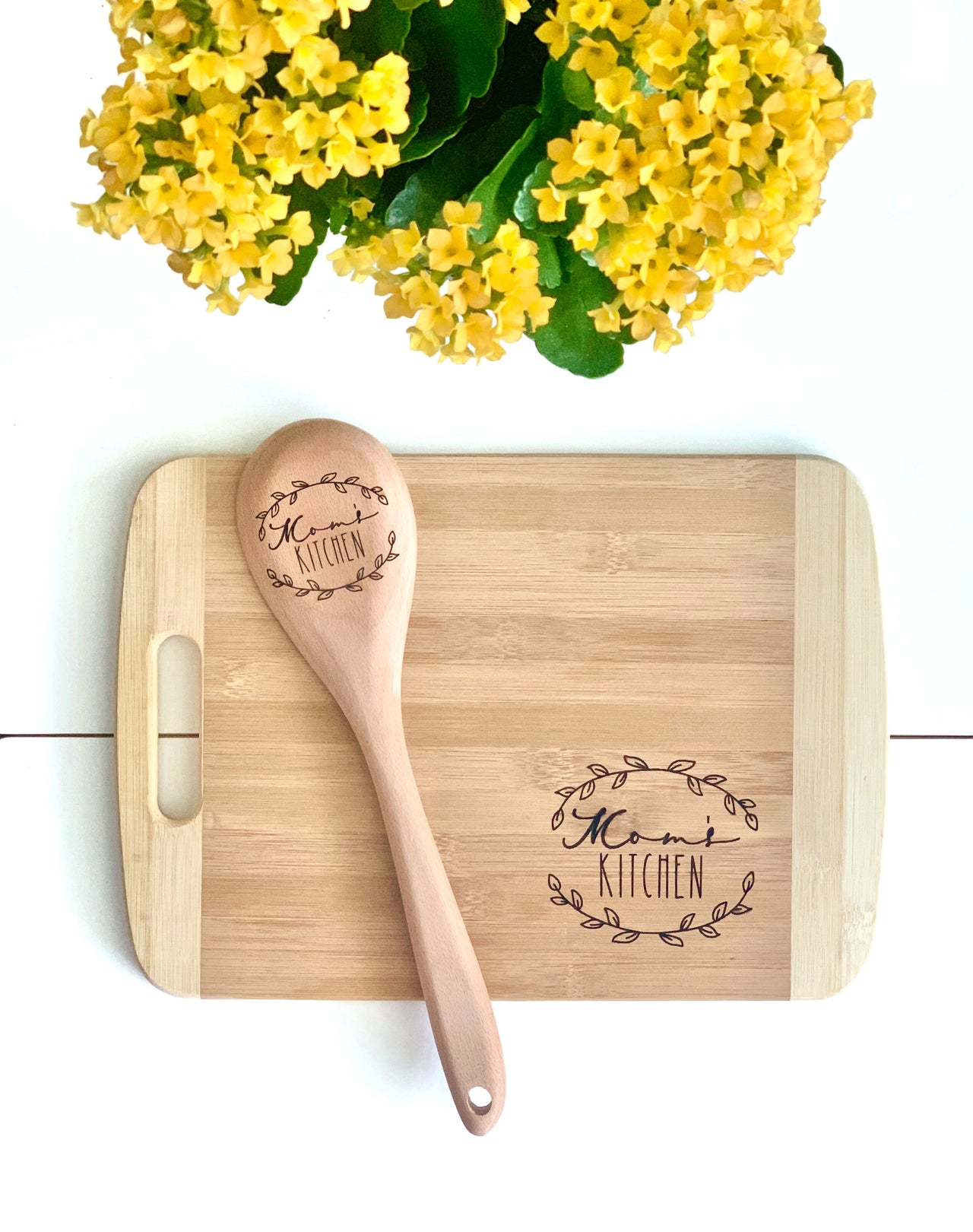 Personalized wooden spoon and cutting board set with "Momi Kitchen" engraving on natural wood grain background
