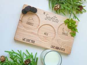 Natural wooden Santa snack plate with engraved sections for cookies, milk, snacks, and personalized names on white surface