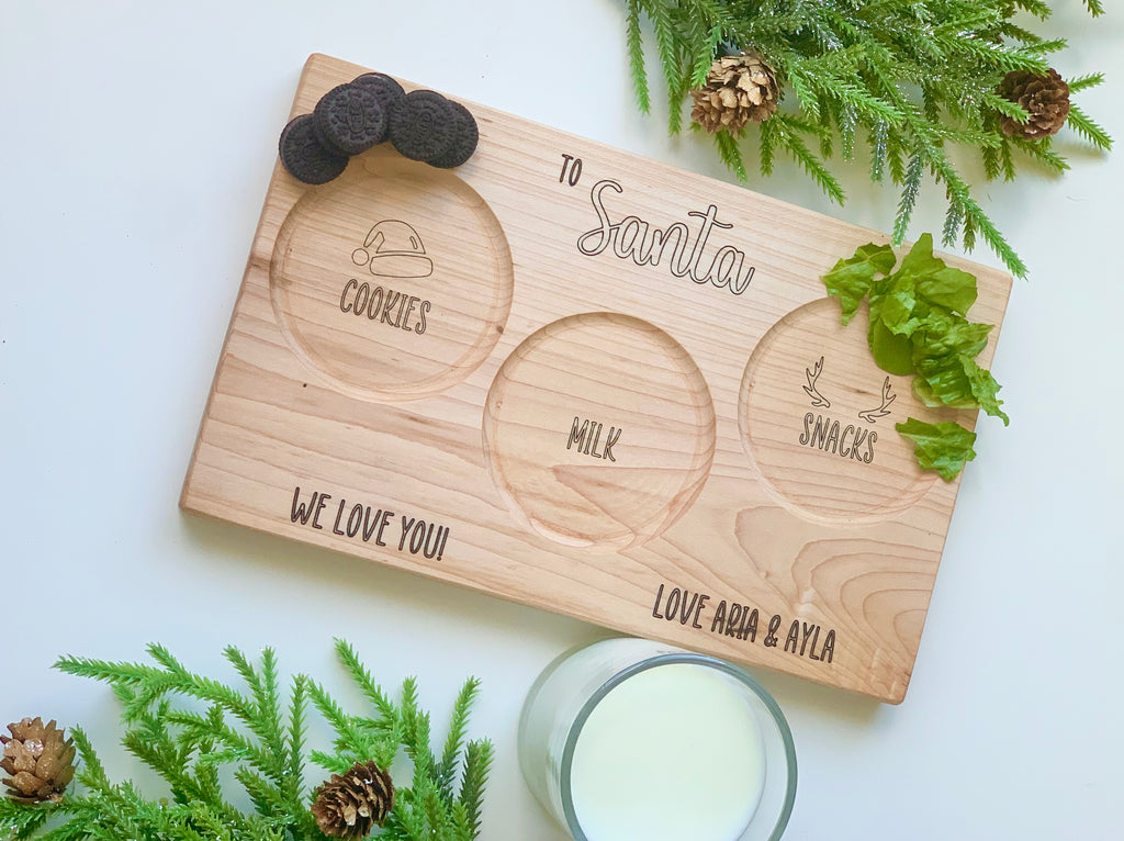 Natural wooden Santa snack plate with engraved sections for cookies, milk, snacks, and personalized names on white surface