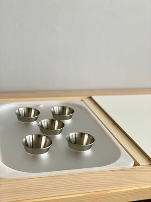 Maple plywood Flisat tabletop insert with white acrylic tray and five small stainless steel cups on light wood frame