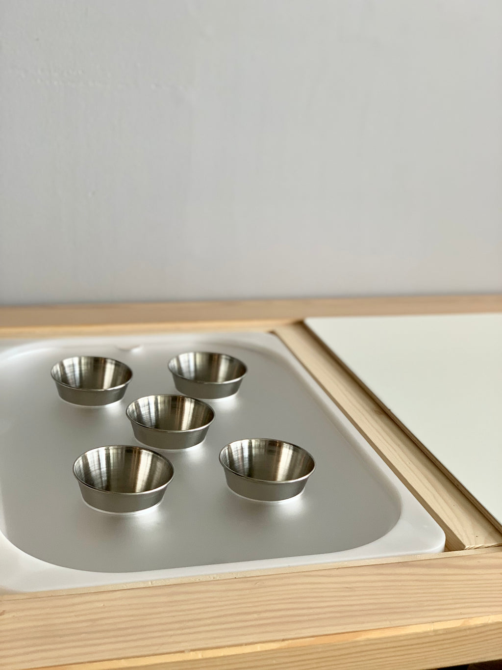 Maple plywood Flisat tabletop insert with white acrylic tray and five small stainless steel cups on light wood frame
