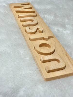 Personalized natural hardwood name puzzle with uppercase and lowercase letters on white textured background