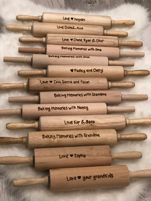 Collection of natural wood personalized rolling pins with custom burned messages and hearts displayed on a soft white surface