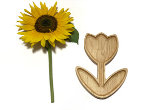Natural wooden tulip-shaped plate or sensory tray next to a bright yellow sunflower on white background