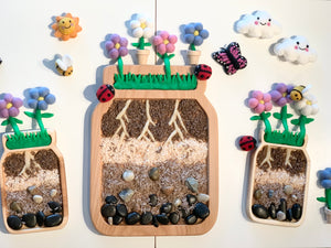 Large jar plate sensory tray with soil layers, roots, rocks, felt flowers, ladybugs, bees, butterfly, and smiling clouds on white background