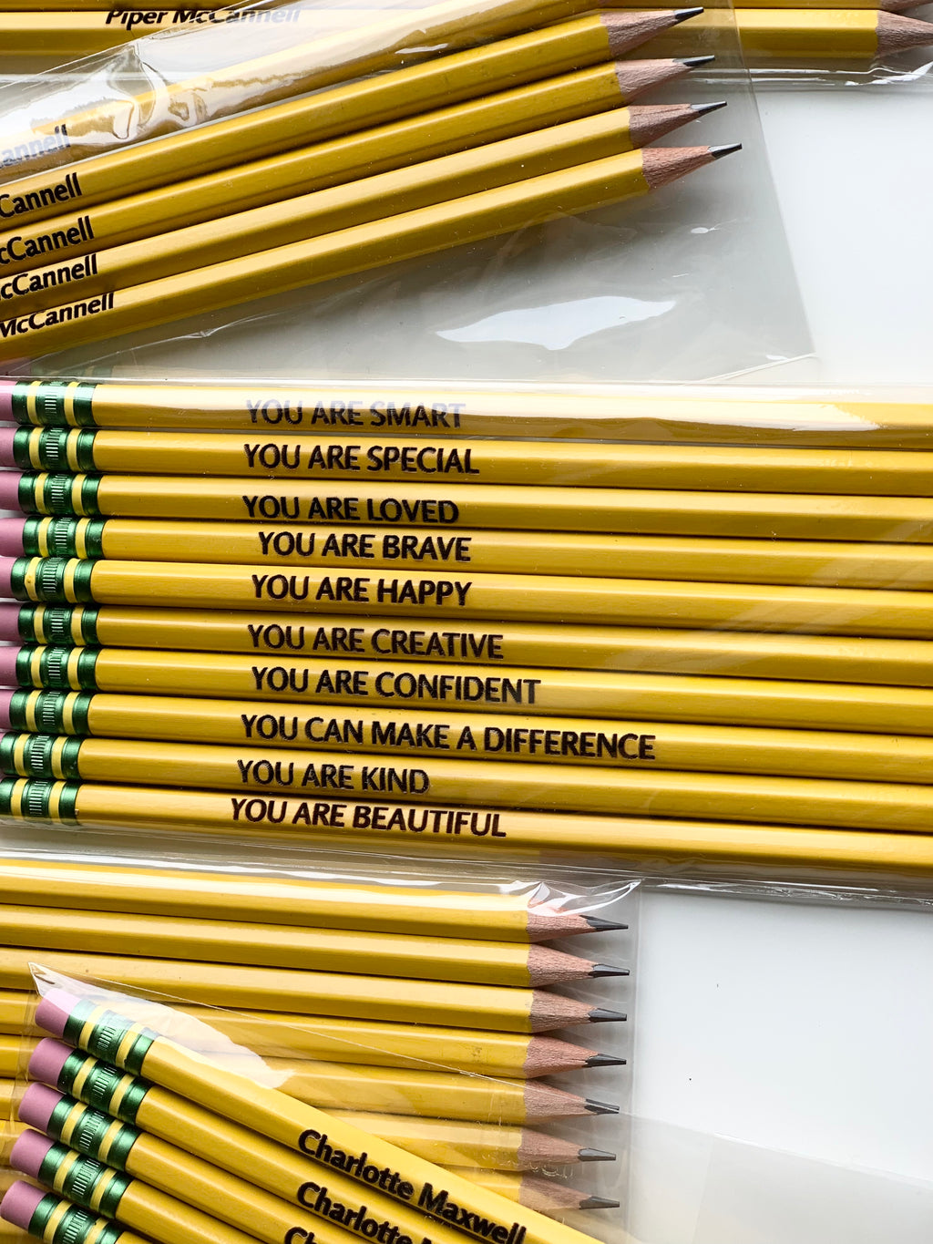 Set of yellow personalized pencils with positive affirmations printed in black on white background