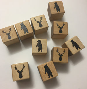 Set of custom 2 inch wooden blocks featuring engraved bear and deer head designs on a light wood surface
