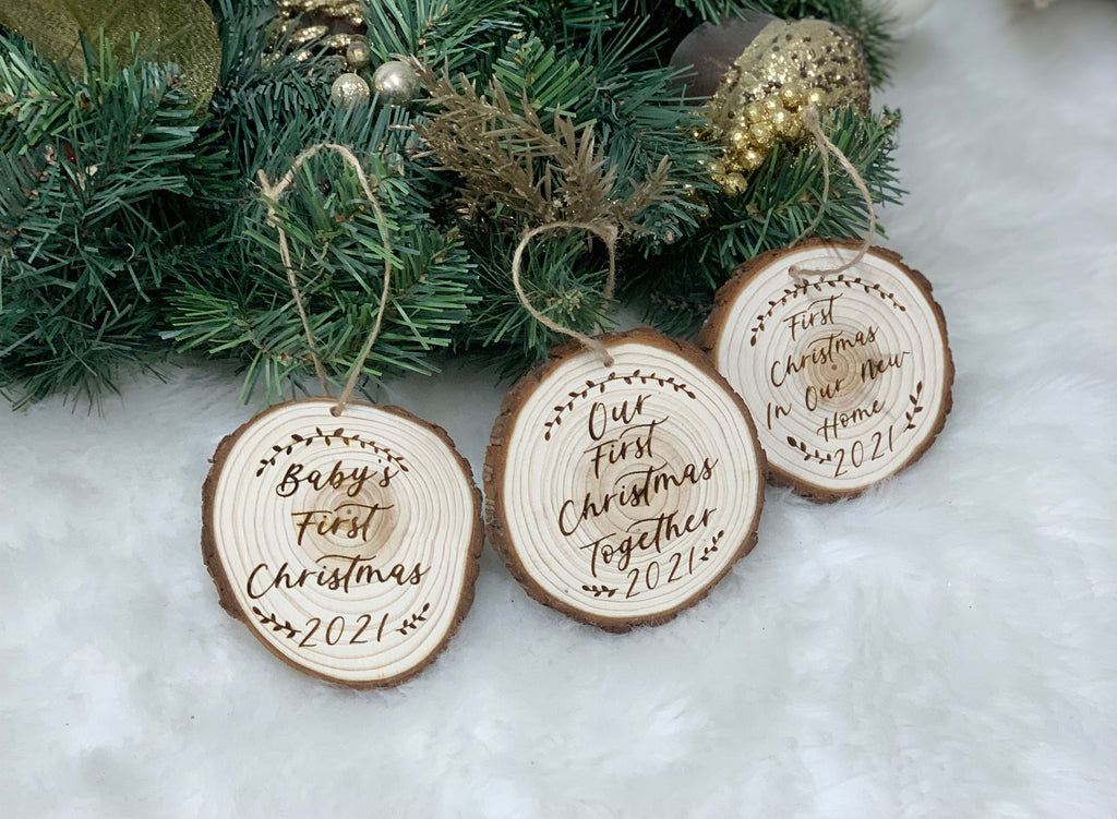Set of three wood burned baby’s first Christmas ornaments with twine hangers on white faux fur background