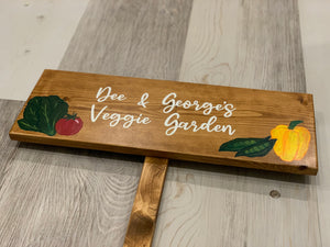 Personalized large wooden vegetable garden sign with white cursive lettering and painted colorful vegetable illustrations on natural wood