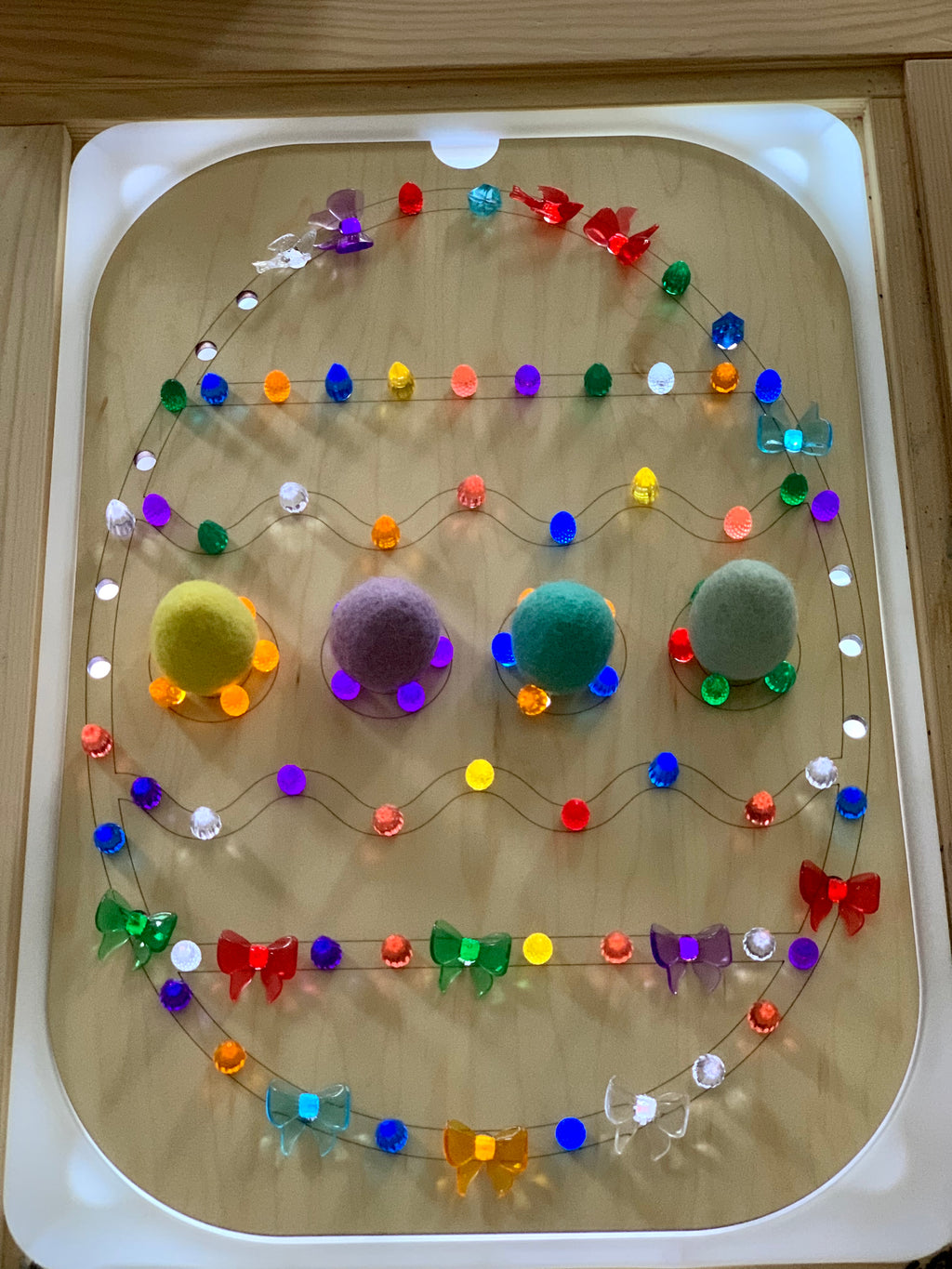 Easter egg-shaped Flisat insert with colorful light pegs and felt balls on wooden board with white frame