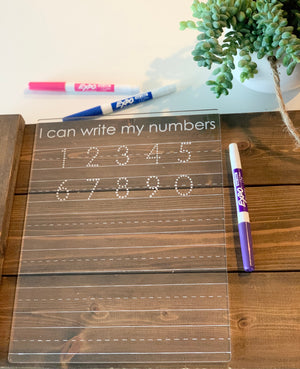 Clear acrylic dry erase board engraved with numbers 1 to 10 for tracing and writing practice with three dry erase markers on wood background