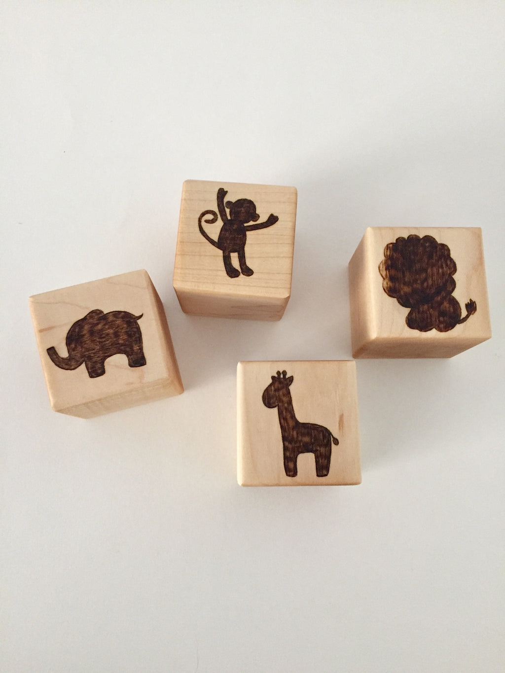 Natural wooden 1.5-inch custom blocks with engraved animal silhouettes of elephant, monkey, lion, and giraffe on white background