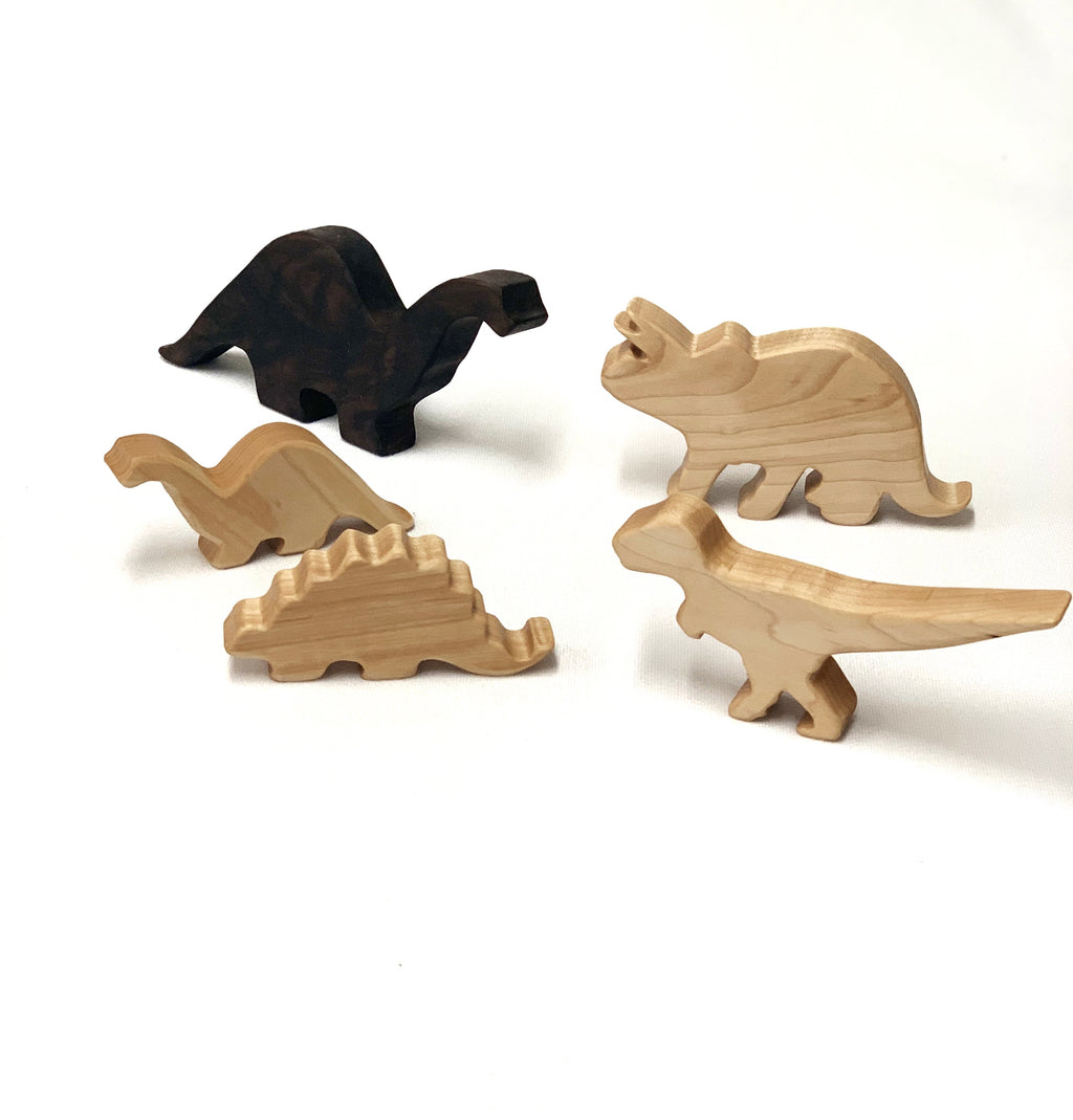 Set of handcrafted natural and dark wood dinosaur toy figurines for imaginative play on white background