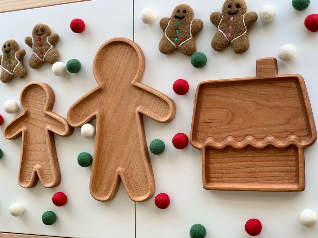 Set of natural wooden sensory trays shaped like gingerbread people and a house surrounded by colorful felt balls