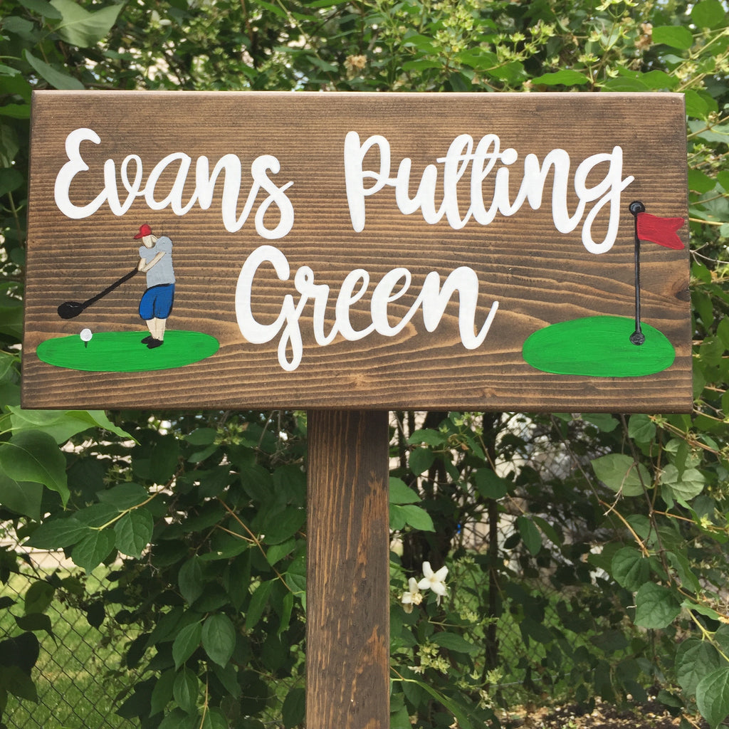 Large custom wooden garden sign with white cursive letters and painted golfer and putting green illustrations on natural wood background