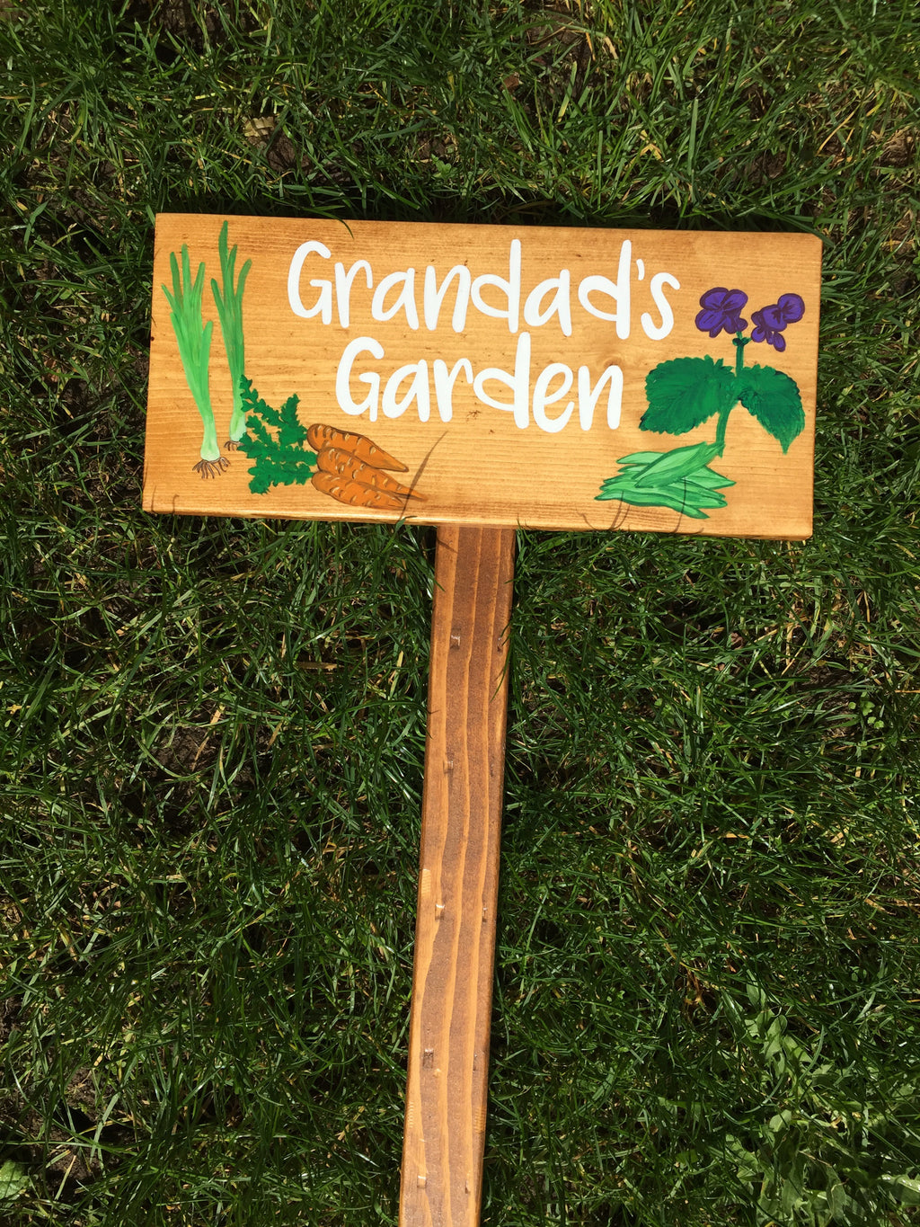 Large personalized wooden garden sign with white lettering and colorful painted vegetables and flowers on natural wood background