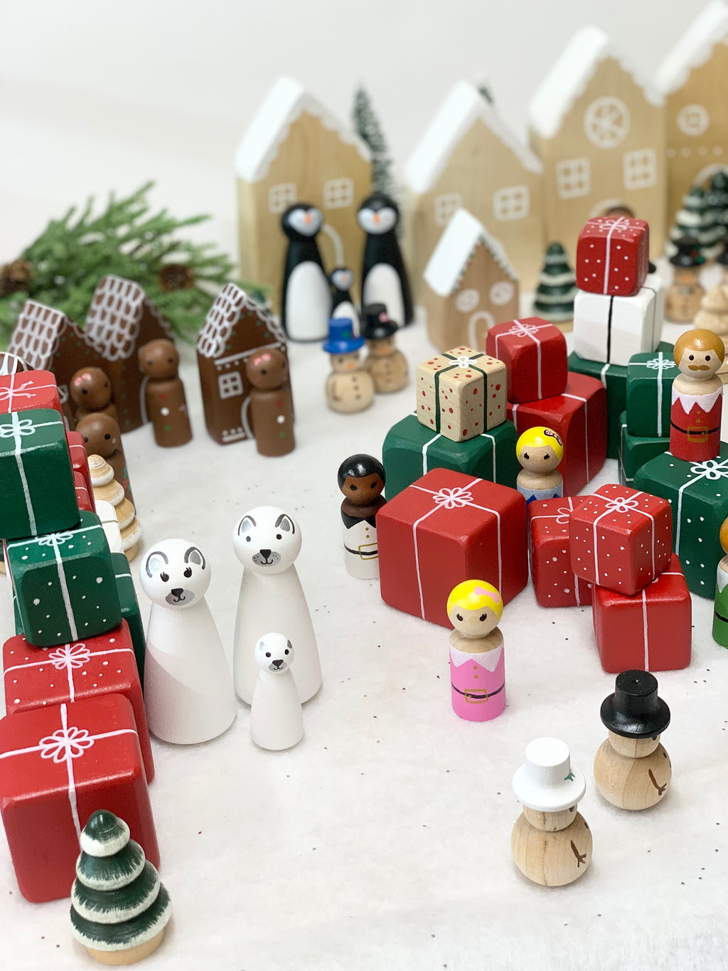Wooden Christmas peg dolls including polar bears, elves, gingerbread houses, penguins, and stacked gift boxes on white background