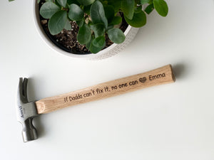 Personalized wooden hammer with laser engraved custom message and heart symbol on natural wood handle near green plant