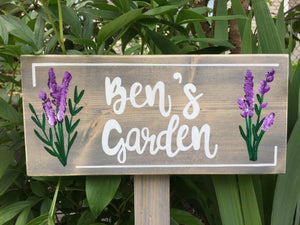 Large personalized wooden garden sign with white cursive letters and painted purple flowers on natural wood background