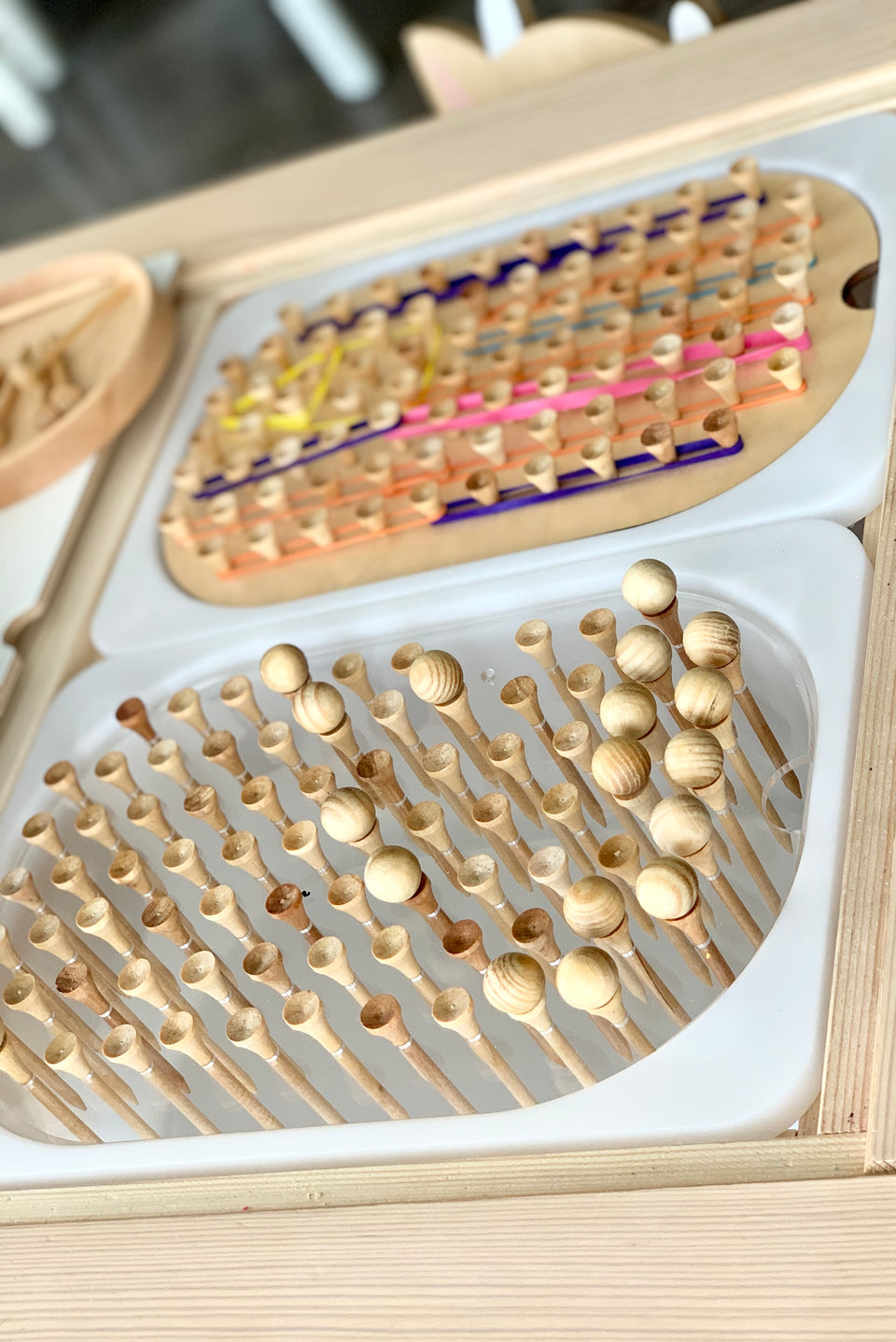 Close-up of wooden small hole pegs in white tray insert for geometric light board tabletop on wooden surface