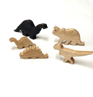 Set of five handmade wooden dinosaur toy figurines in natural and dark wood tones on white background