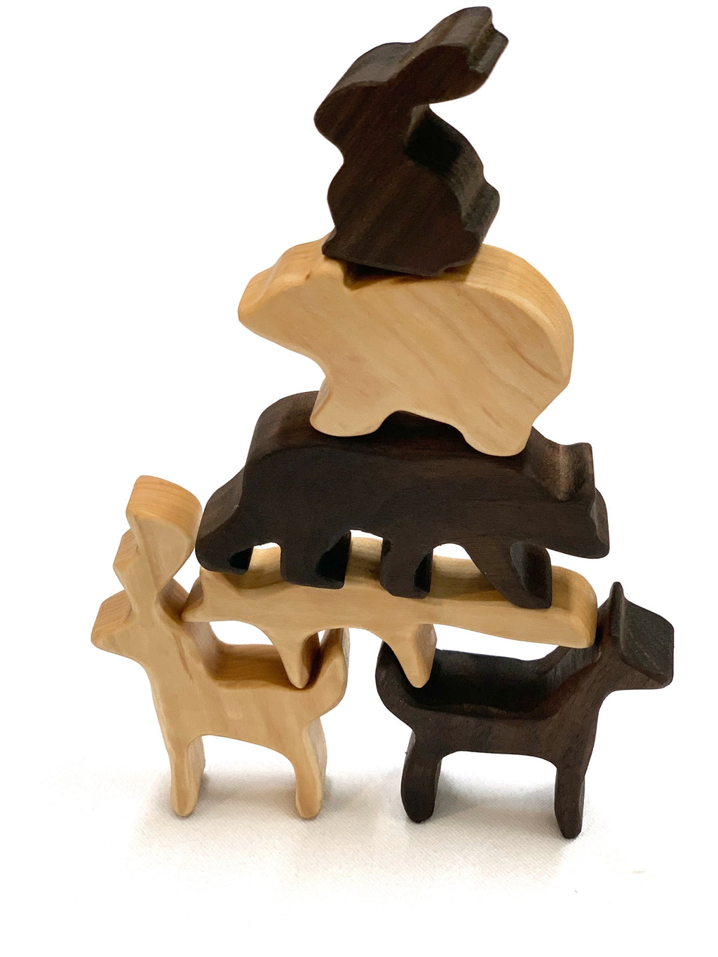Stacked natural and dark wooden woodland animal toy figurines on white background for imaginative play