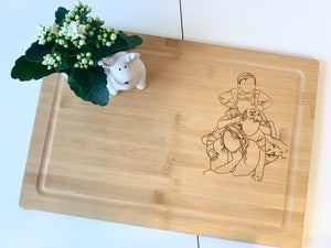 Personalized bamboo cutting board with engraved cowboy and dog design and small white flower pot on white table