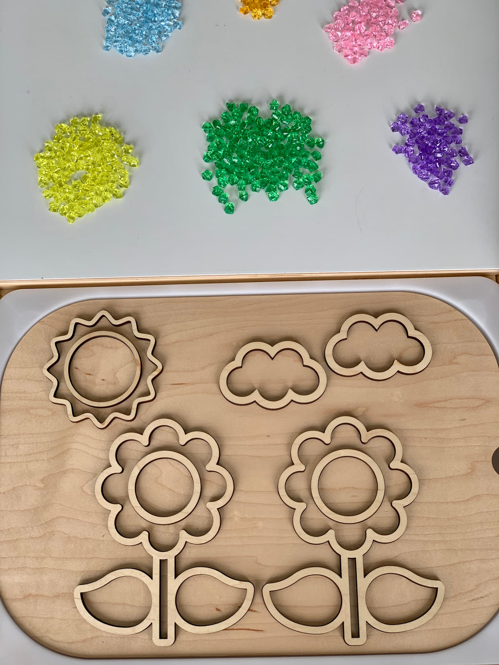 Mini acrylic treasure gems in assorted colors with wooden flower, sun, and cloud puzzle base on white and wood surfaces