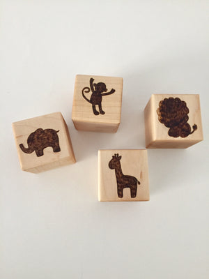 Four 2-inch custom wood blocks with engraved animal designs including elephant, monkey, lion, and giraffe on a white background