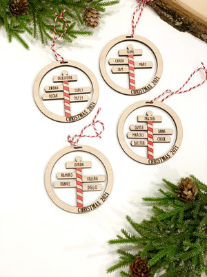 Set of four round wooden North Pole family Christmas ornaments with personalized names and red striped poles on white background