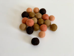 Assortment of 20 small felt balls in tangerine, brown, and beige tones on white background