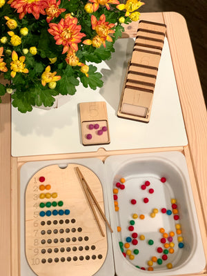 Counting 1-10 Flisat table top insert with wooden number cards, colored pom poms, tweezers, and a flower pot on wooden table