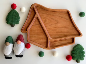 Whimsical 3D wooden house-shaped plate with smooth edges surrounded by felt gnome and tree decorations on white background