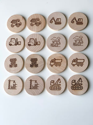 Natural wooden memory game discs engraved with construction vehicle and work site illustrations arranged in rows on white background