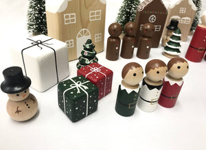 Small painted wooden peg dolls including snowman, elves, presents, trees, and houses on white surface