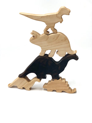 Stacked natural and dark wooden dinosaur toy figurines on white background for imaginative play and motor skills development