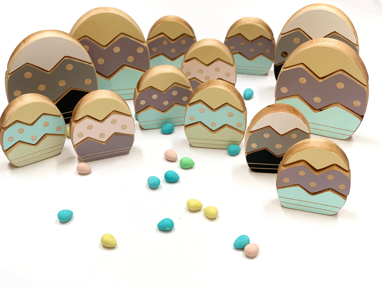 Hardwood stacking Easter eggs in pastel and neutral colors with painted zigzag and dot patterns on white background