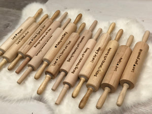 Row of personalized wooden rolling pins with custom engraved baking and love messages on light wood grain surface