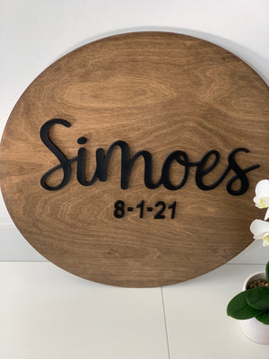 Round wooden guest book alternative sign with black 3D cursive last name and date on natural wood background