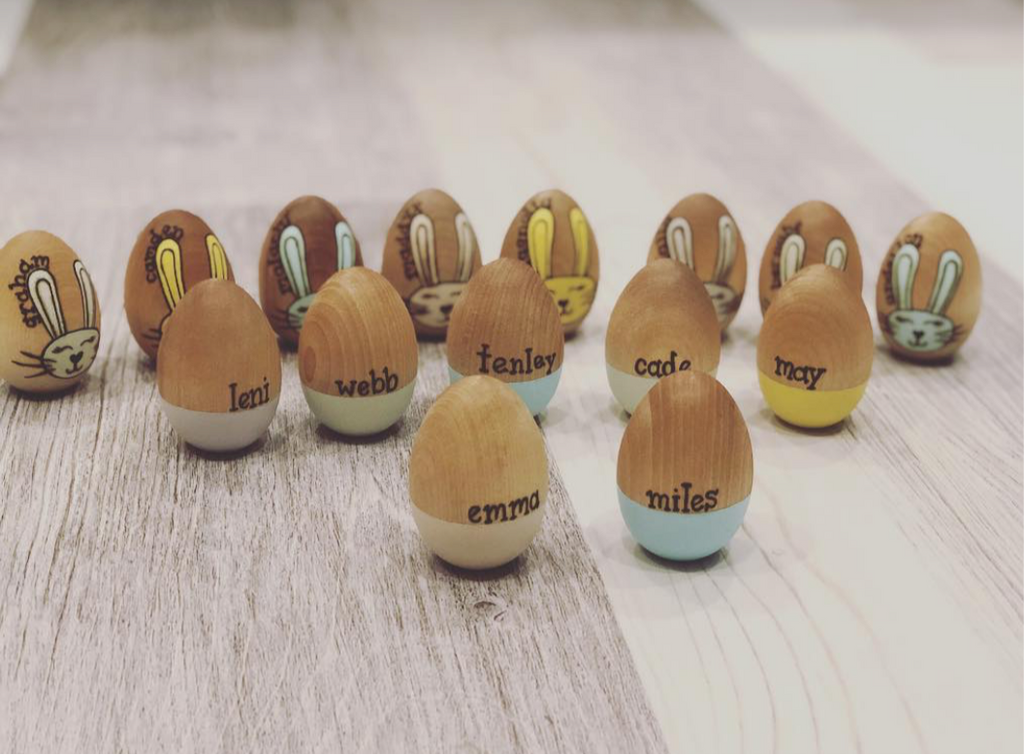 Personalized wooden Easter eggs with pastel bases and hand-painted bunny faces displayed on wood surface