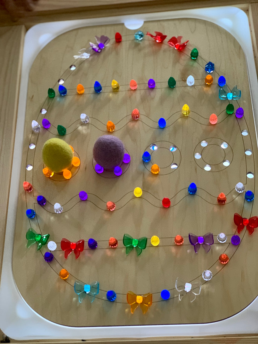 Light Up Easter Egg Flisat Insert with colorful pegs, felt balls, and butterfly-shaped decorations on wooden tabletop