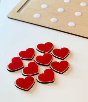 Wooden cookie sheet with white velcro dots and red heart-shaped cookies with hook and loop backing on white surface