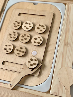 Wooden cookie sheet with nine circular cookies featuring wooden chips and a spatula on light wood surface