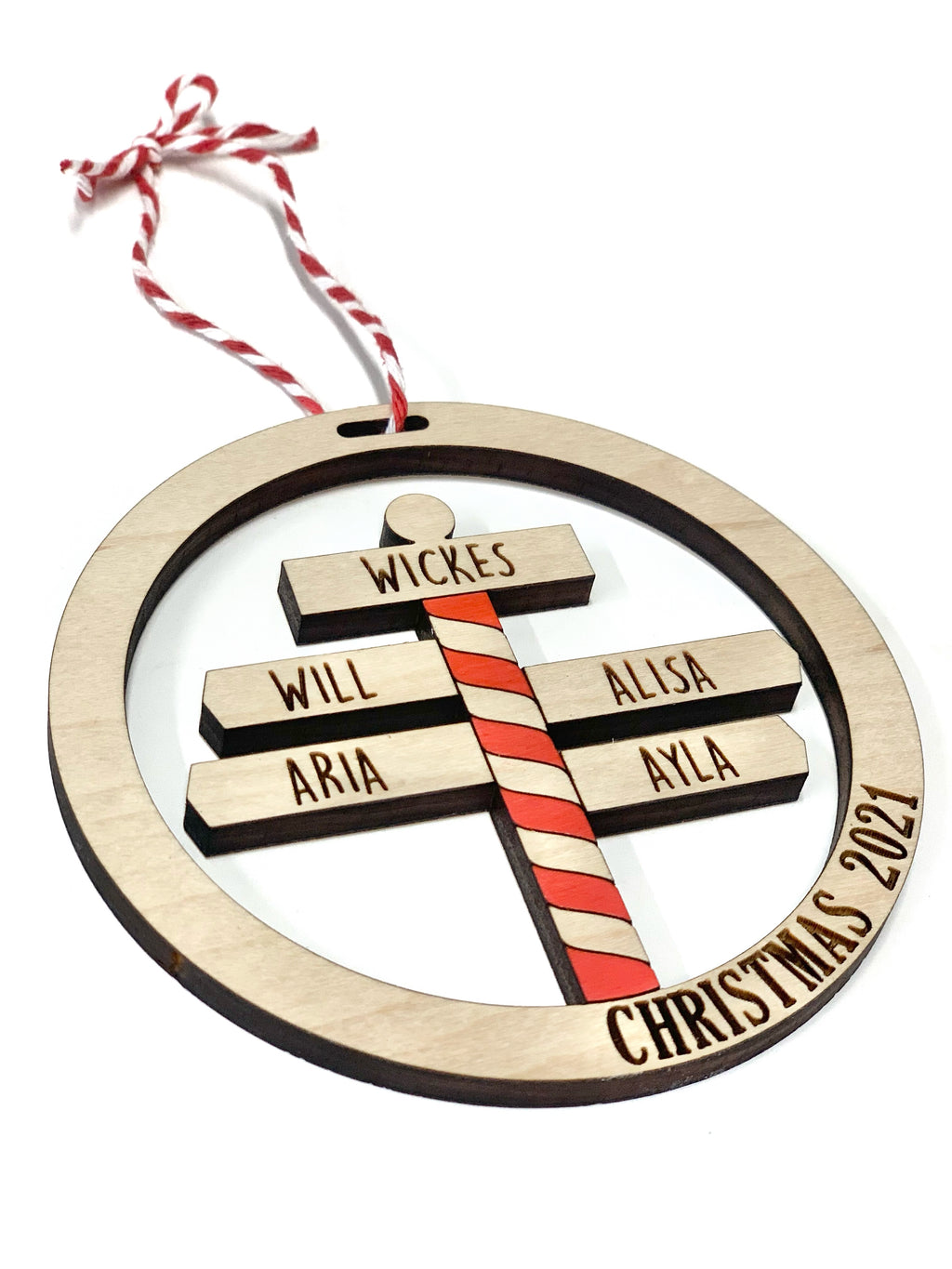 Round wooden North Pole family Christmas ornament with five engraved names and red striped candy cane pole design