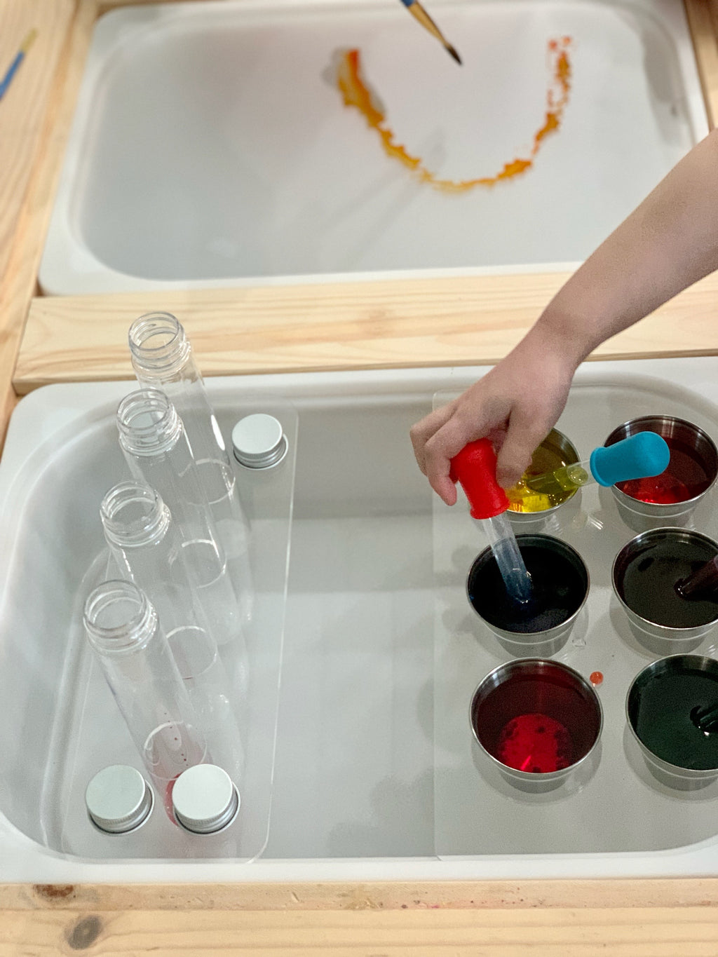 Clear acrylic Flisat table top insert with plastic test tubes and child using dropper to mix colorful liquids