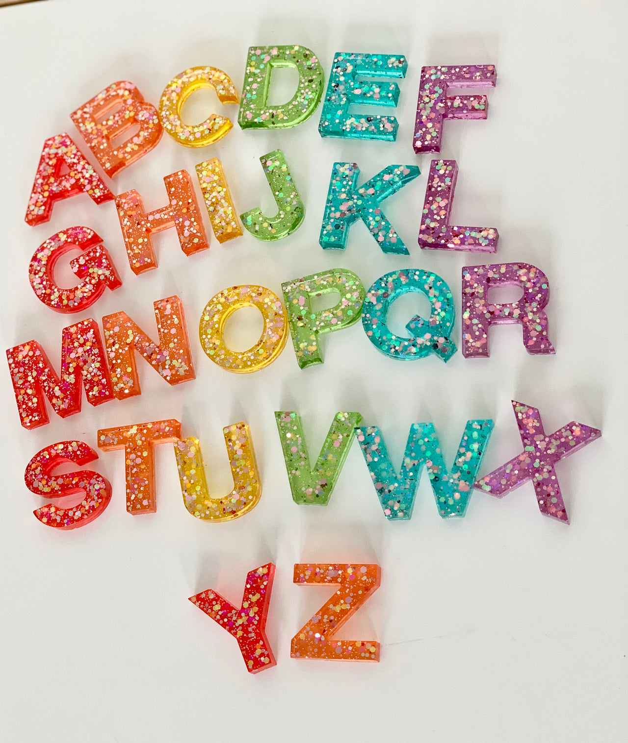 Rainbow glitter resin uppercase alphabet letters A to Z arranged on white background